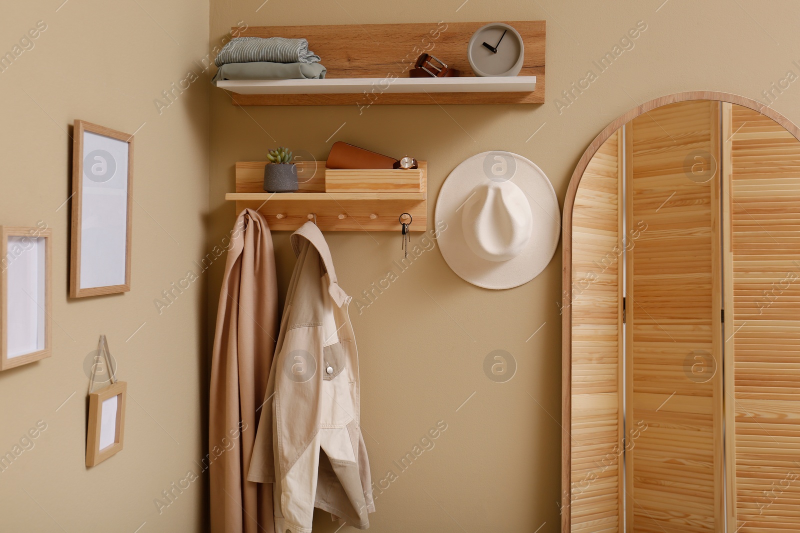 Photo of Hallway interior with stylish accessories and wooden hanger for keys on beige wall