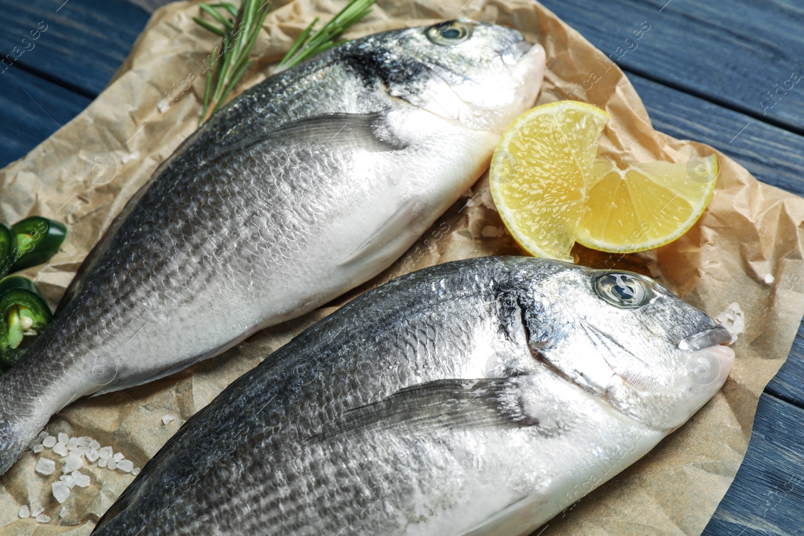 Photo of Raw dorada fish on blue wooden table, closeup