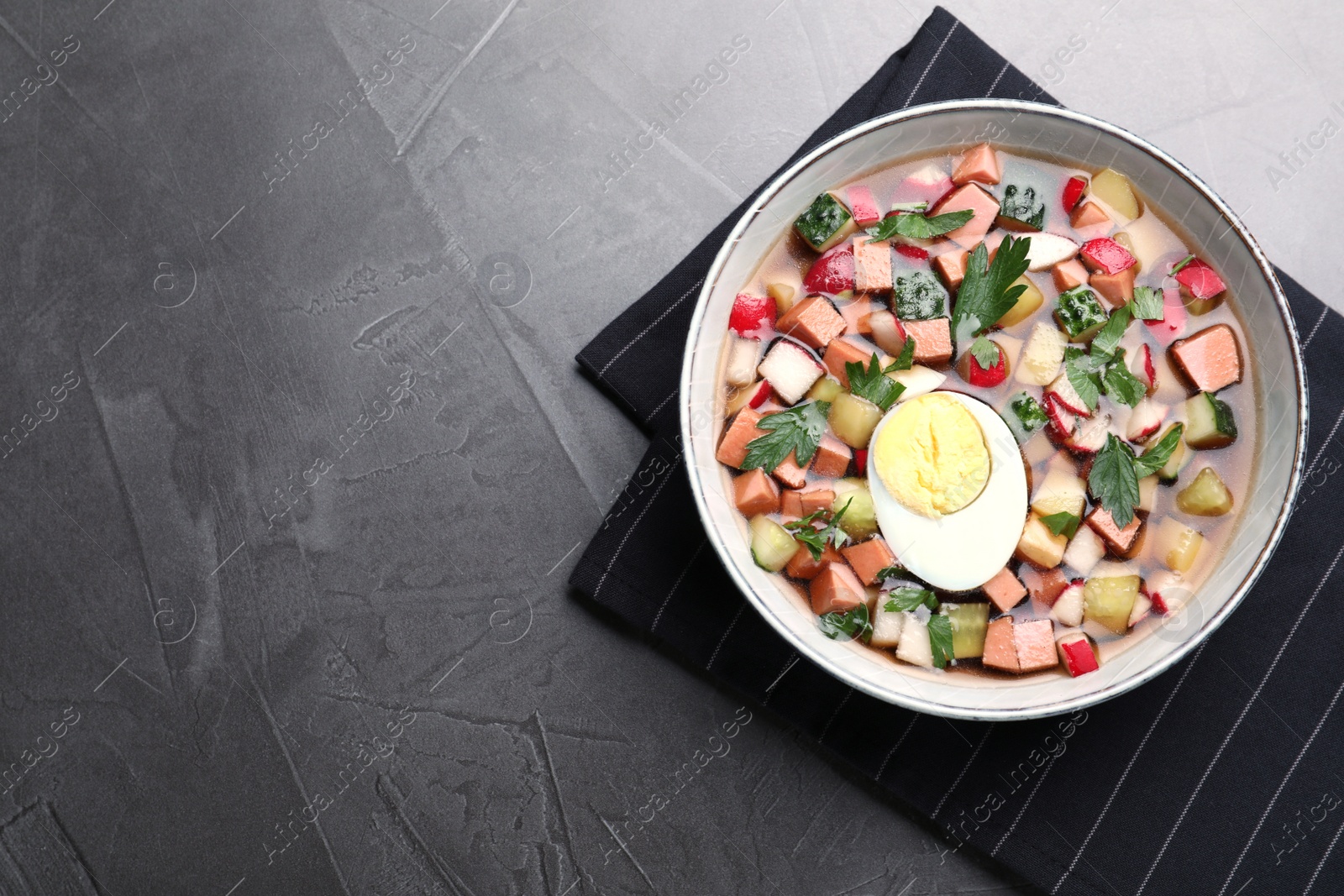 Photo of Delicious cold okroshka with kvass on grey table, top view and space for text. Traditional Russian summer soup