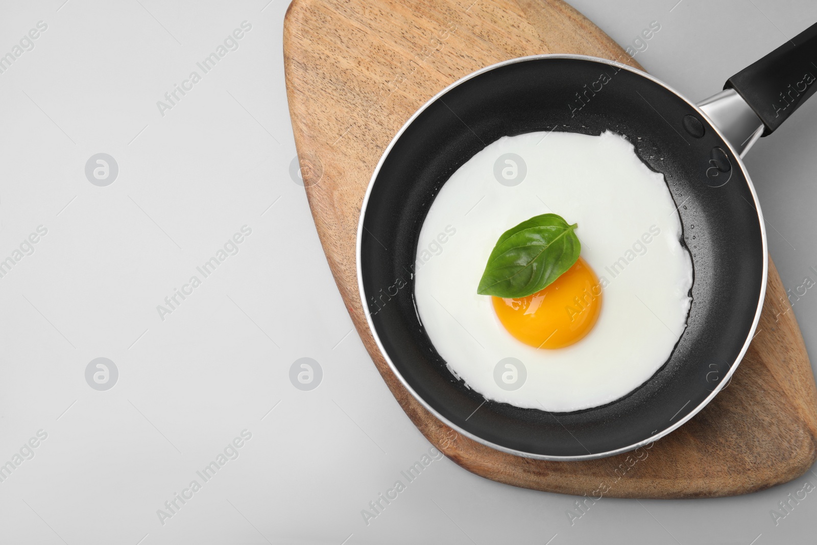Photo of Pan with tasty fried egg on light grey background, top view. Space for text