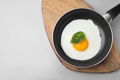 Pan with tasty fried egg on light grey background, top view. Space for text