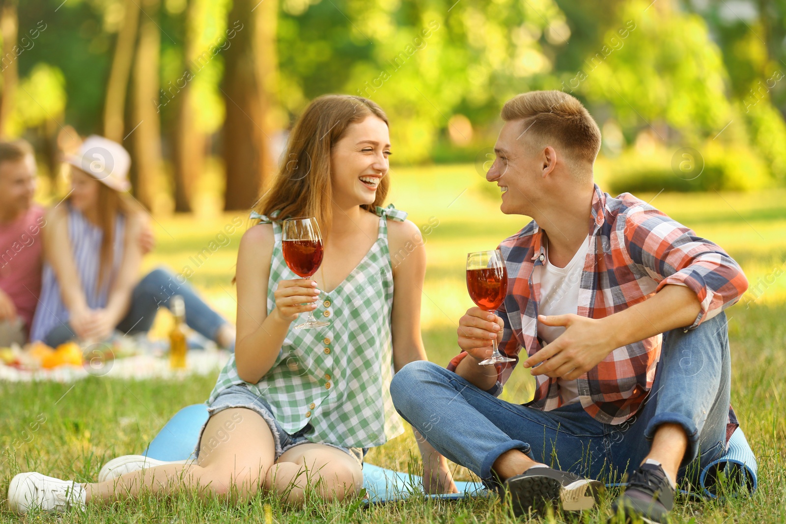 Photo of Young couple enjoying picnic in park on summer day