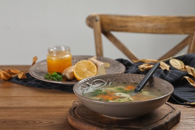 Bowl of fresh homemade soup to cure flu on wooden table