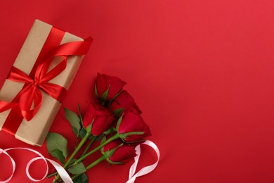Photo of Beautiful gift box and roses on red background, flat lay with space for text. Valentine's day celebration