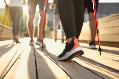 Photo of Group of people practicing Nordic walking with poles outdoors on sunny day, closeup