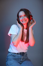 Portrait of beautiful woman with headphones on color background