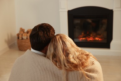 Lovely couple spending time together near fireplace at home, back view