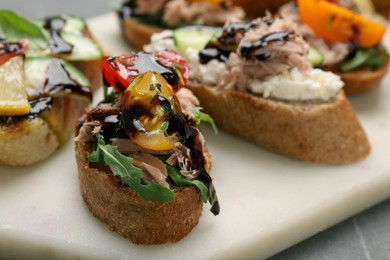 Photo of Delicious bruschettas with balsamic vinegar and different toppings on table, closeup