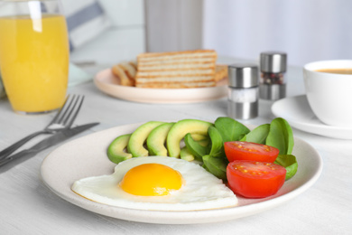 Photo of Tasty breakfast with heart shaped fried egg served on white wooden table
