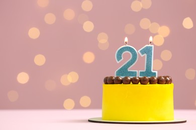 Photo of Coming of age party - 21st birthday. Delicious cake with number shaped candles on pink background against blurred lights, space for text
