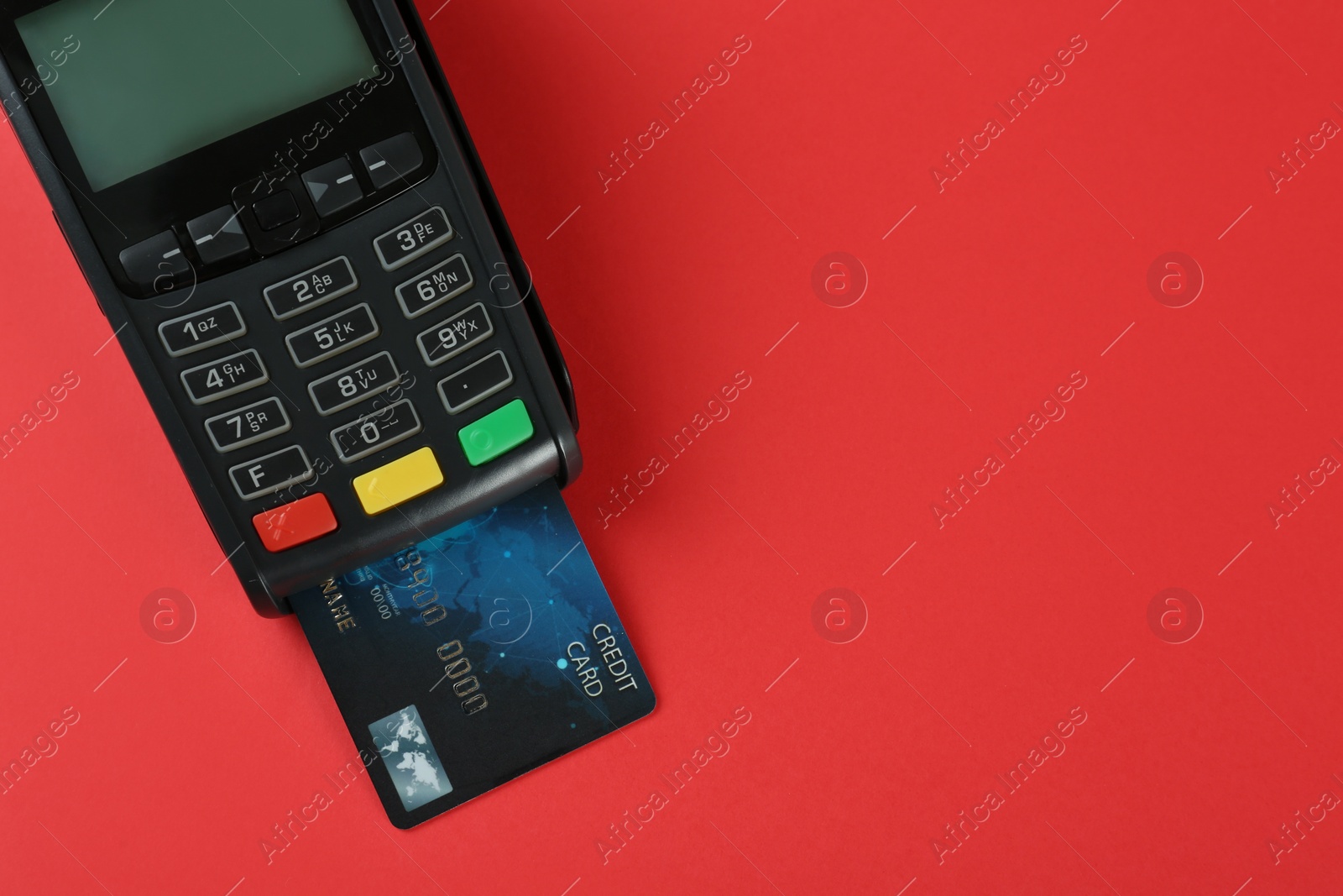 Photo of New modern payment terminal with credit card on red background, top view. Space for text