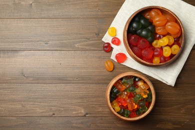 Photo of Delicious gummy candies on wooden table, flat lay. Space for text