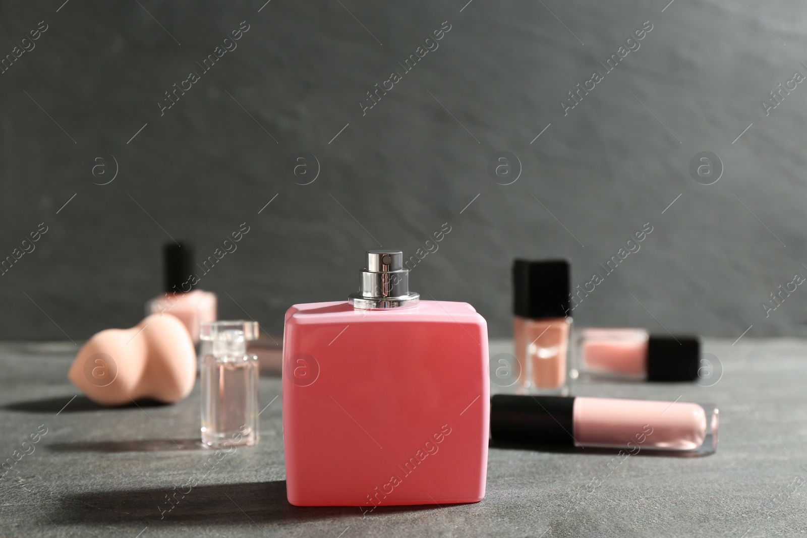 Photo of Bottle of perfume and cosmetics on grey table