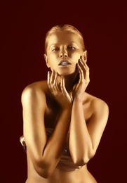 Portrait of beautiful lady with gold paint on skin against color background