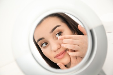 Photo of Mirror reflection of young woman putting contact lens in her eye