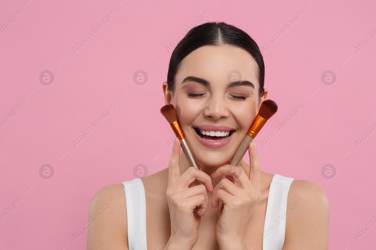 Photo of Happy woman with different makeup brushes on pink background. Space for text