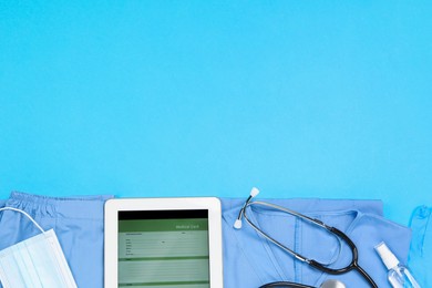 Photo of Flat lay composition with medical uniform and stethoscope on light blue background. Space for text