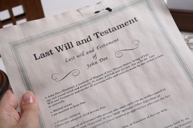 Photo of Woman holding last will and testament at table, closeup