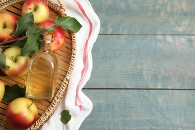 Photo of Natural apple vinegar and fresh fruits on blue wooden table, flat lay. Space for text