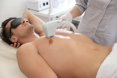 Young man undergoing laser epilation procedure in beauty salon