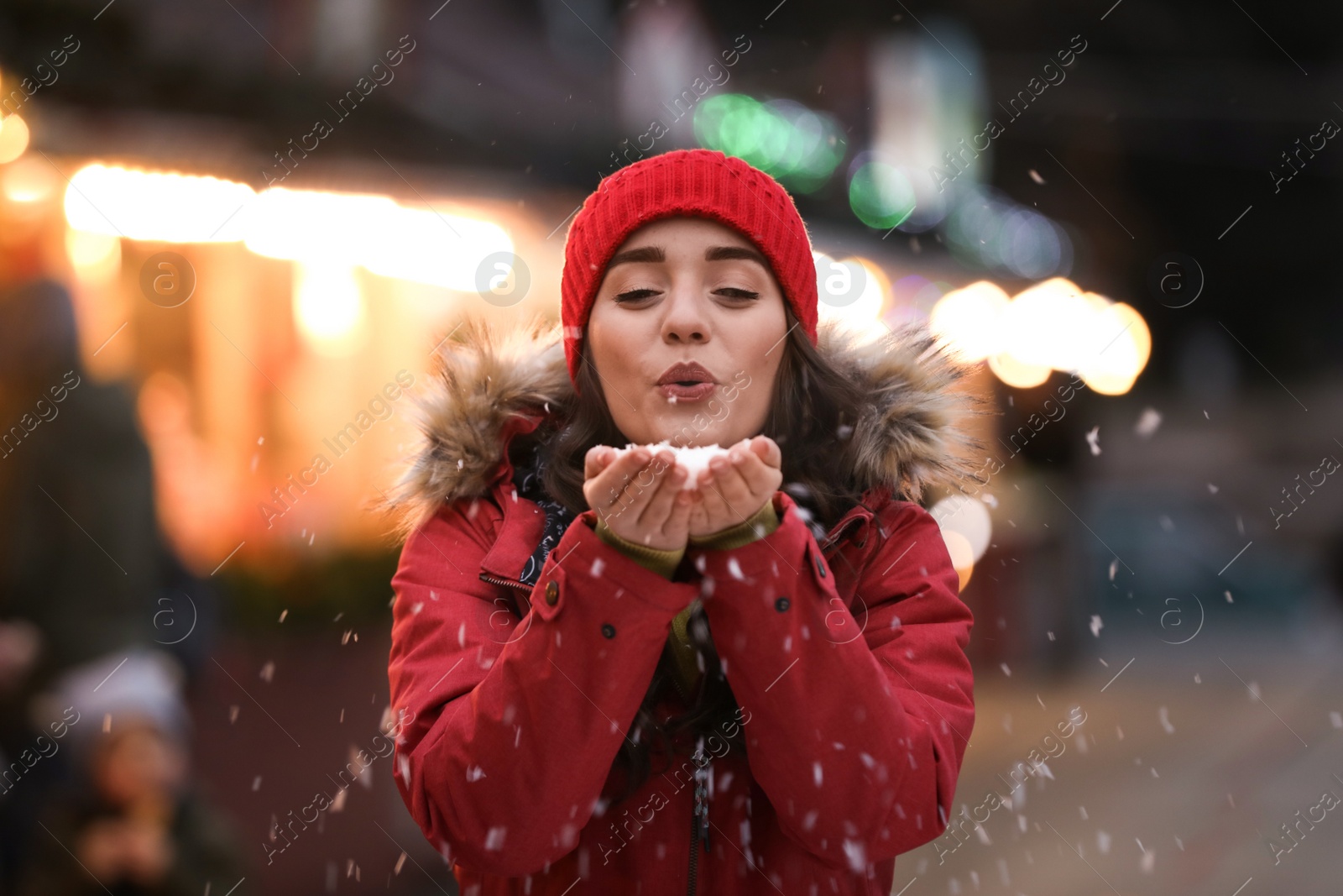 Photo of Happy young woman blowing snow at winter fair. Christmas celebration