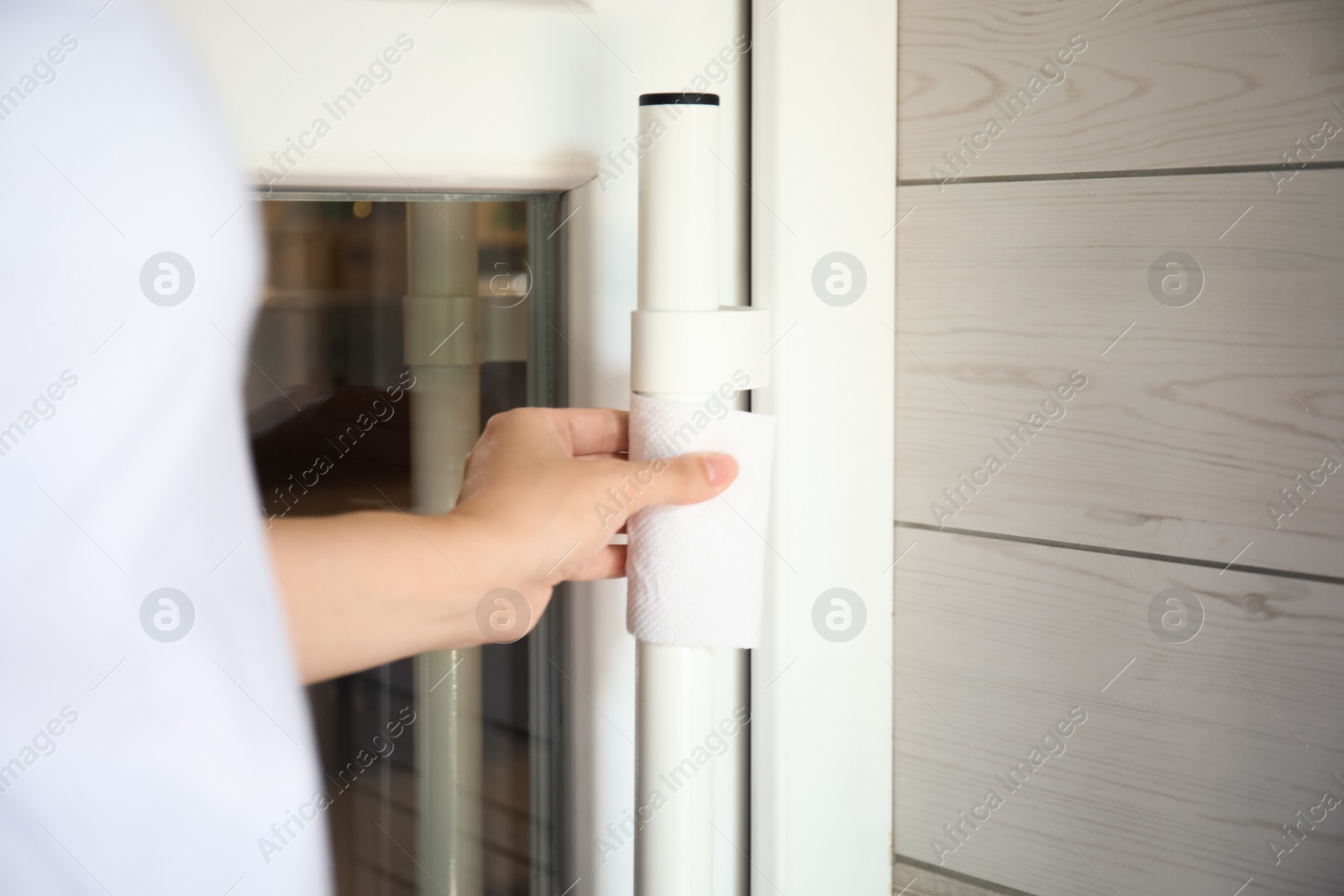 Photo of Woman using tissue paper to open door, closeup