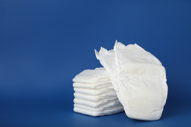 Photo of Stack of diapers on blue background. Space for text