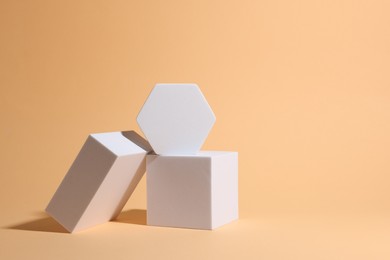 Photo of Scene for product presentation. Podiums of different geometric shapes on pale orange background, space for text