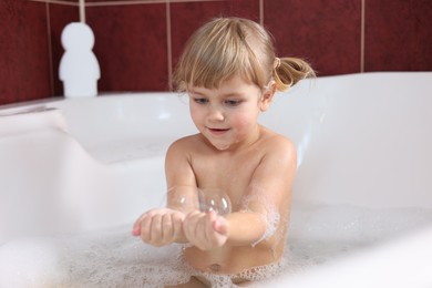 Photo of Little girl having fun in bathtub at home