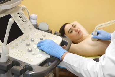 Photo of Mammologist conducting ultrasound examination of woman's breast in clinic, closeup