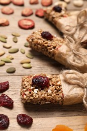 Photo of Tasty granola bars and ingredients on wooden table