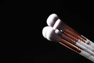 Photo of Set of makeup brushes against dark background. Space for text