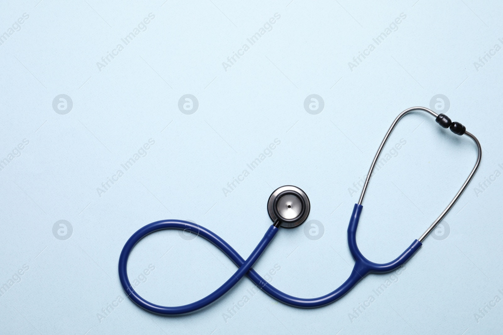 Photo of Stethoscope on light blue background, top view. Space for text