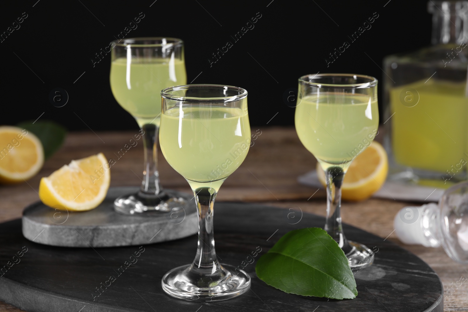 Photo of Tasty limoncello liqueur and green leaf on table