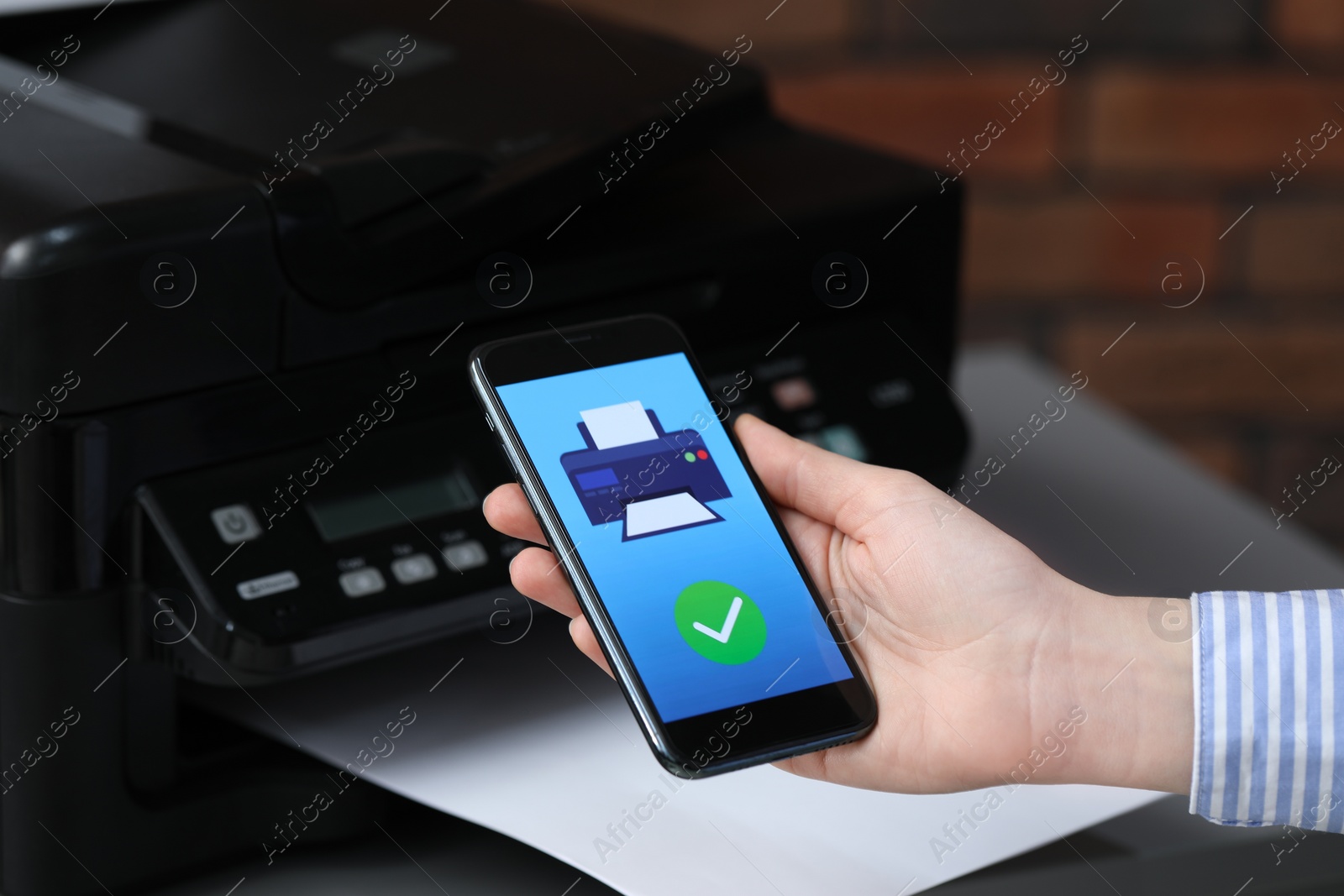 Photo of Man using printer management application on mobile phone indoors, closeup. Image on device screen.