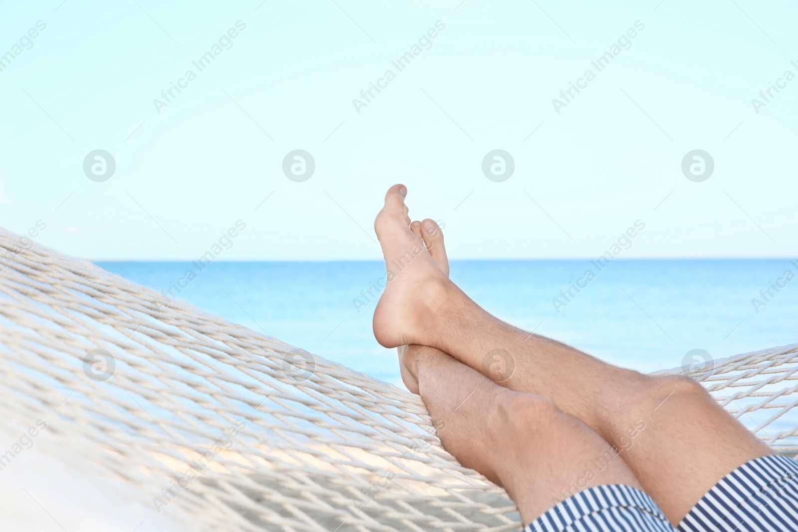 Photo of Young man resting in hammock at seaside. Summer vacation