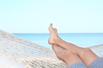 Photo of Young man resting in hammock at seaside. Summer vacation