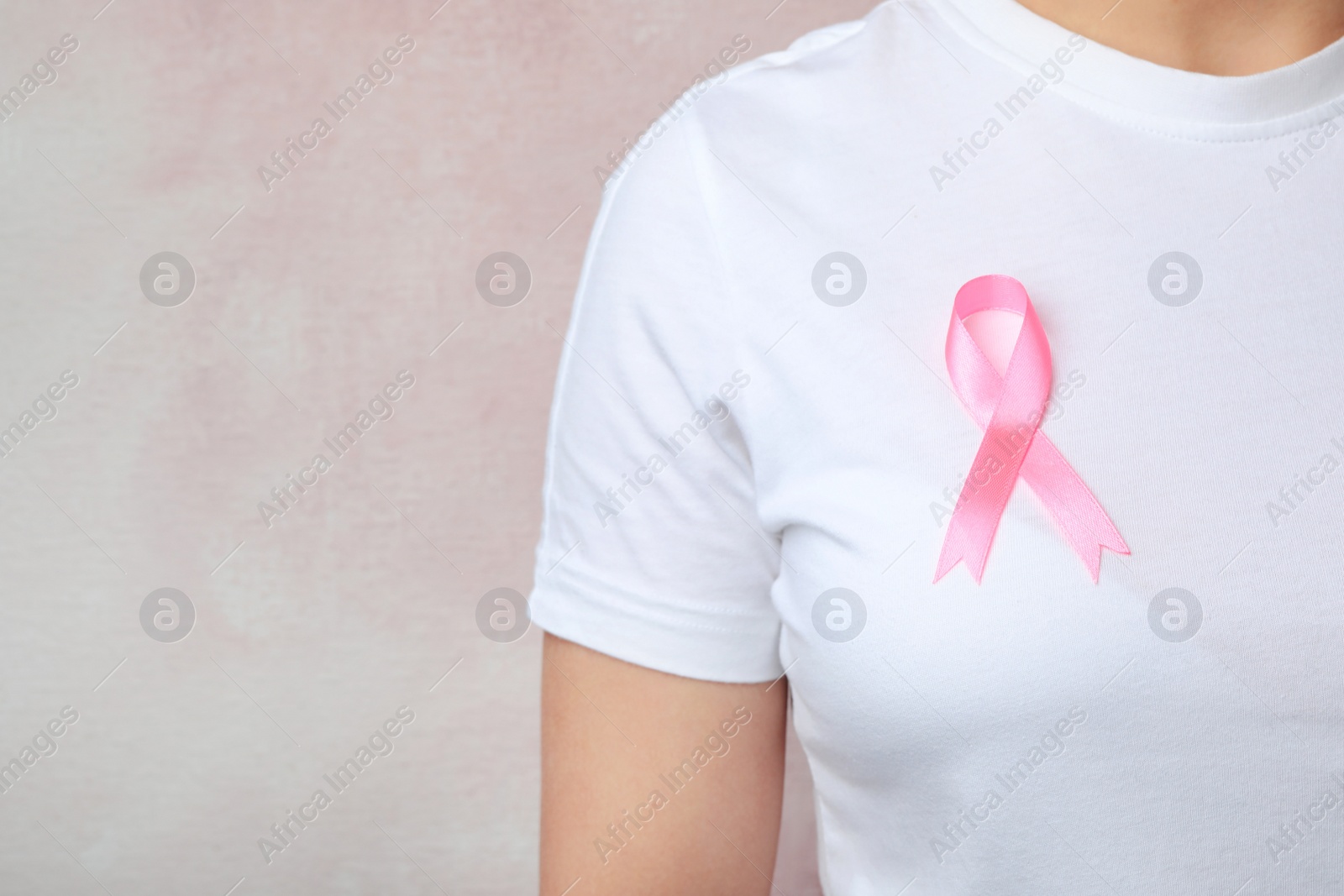 Photo of Woman with pink ribbon on color background, space for text. Breast cancer awareness