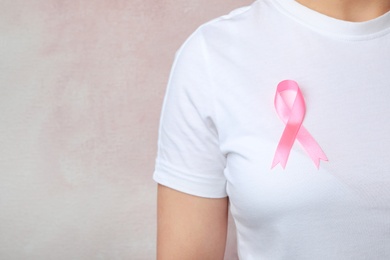Woman with pink ribbon on color background, space for text. Breast cancer awareness
