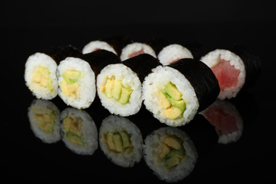 Photo of Delicious sushi rolls on black mirror surface