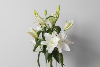 Photo of Beautiful bouquet of lily flowers in glass vase on white background