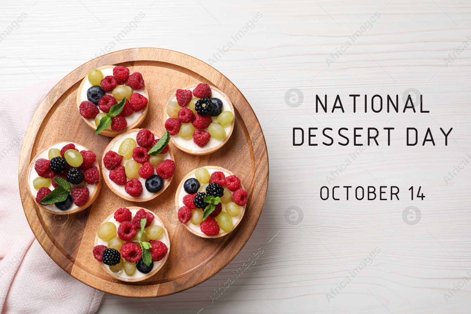 Image of National Dessert Day, October 14. Delicious tartlets with fresh berries on white wooden table, top view