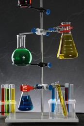 Photo of Retort stand and laboratory glassware with liquids on table against grey background