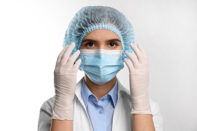 Photo of Doctor with medical gloves, mask and cap on white background