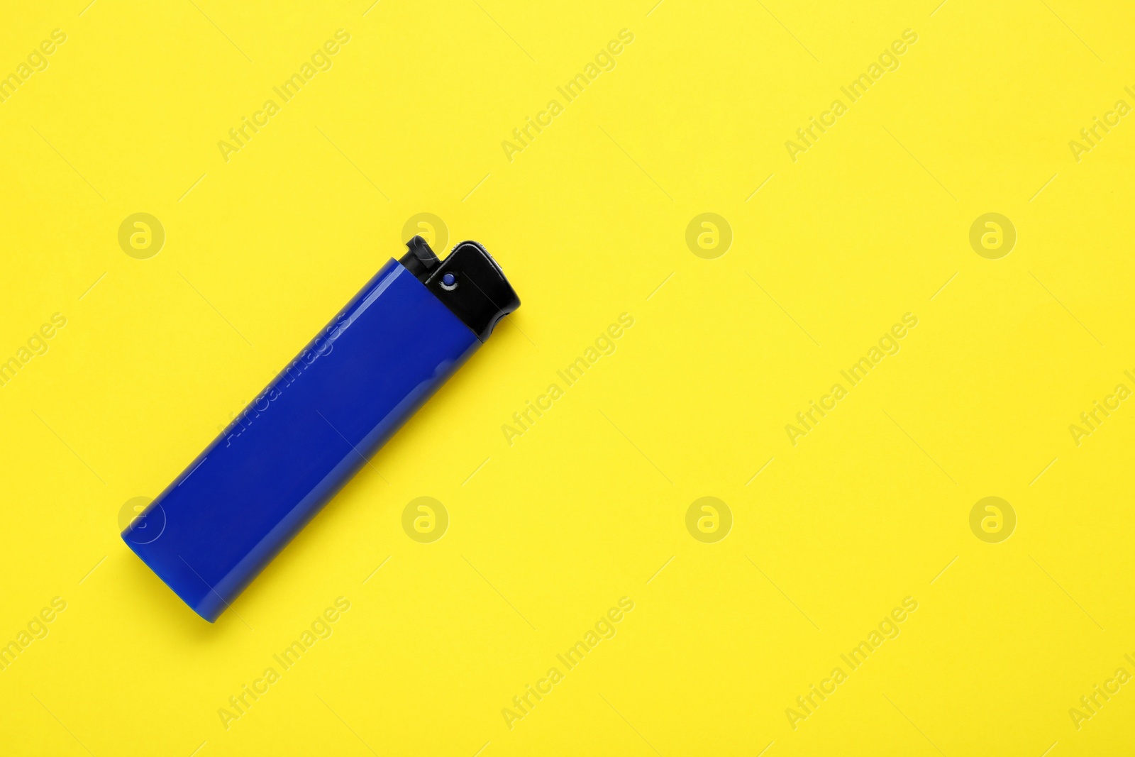 Photo of Stylish small pocket lighter on yellow background, top view. Space for text