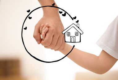 Image of Father holding hands with child and illustration of house indoors, closeup. Adoption concept