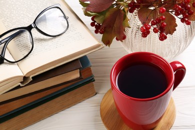 Photo of Cup with hot drink, stackbooks and glasses on white wooden table, above view. Autumn atmosphere