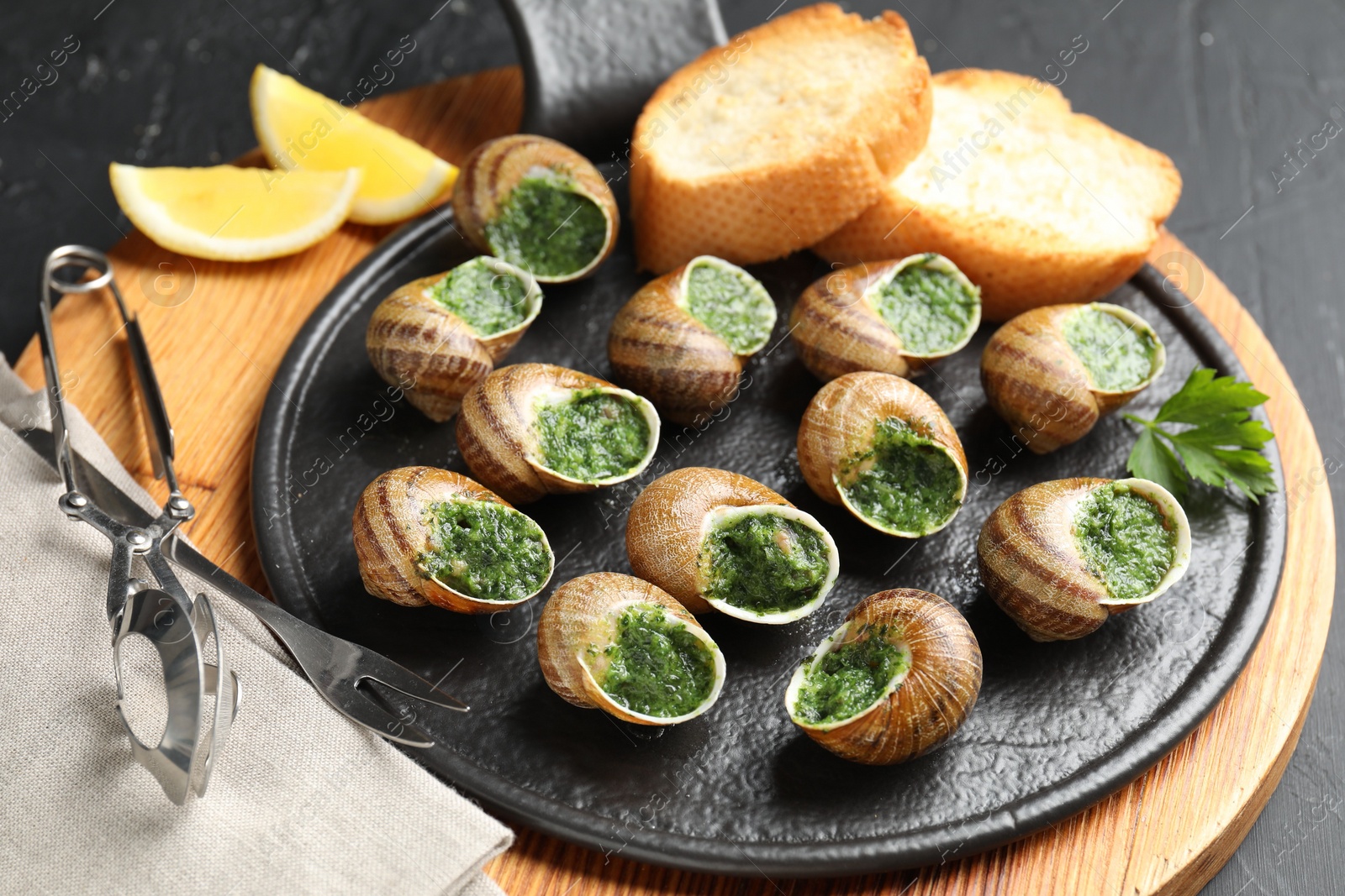 Photo of Delicious cooked snails served on grey table