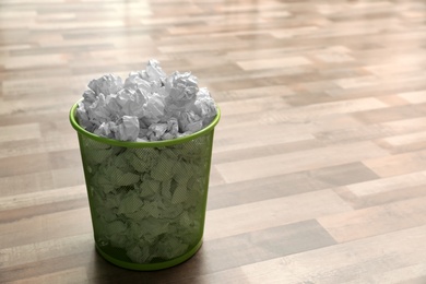 Metal bin with crumpled paper on floor, space for text