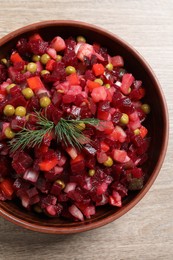 Bowl of delicious fresh vinaigrette salad on wooden table, top view